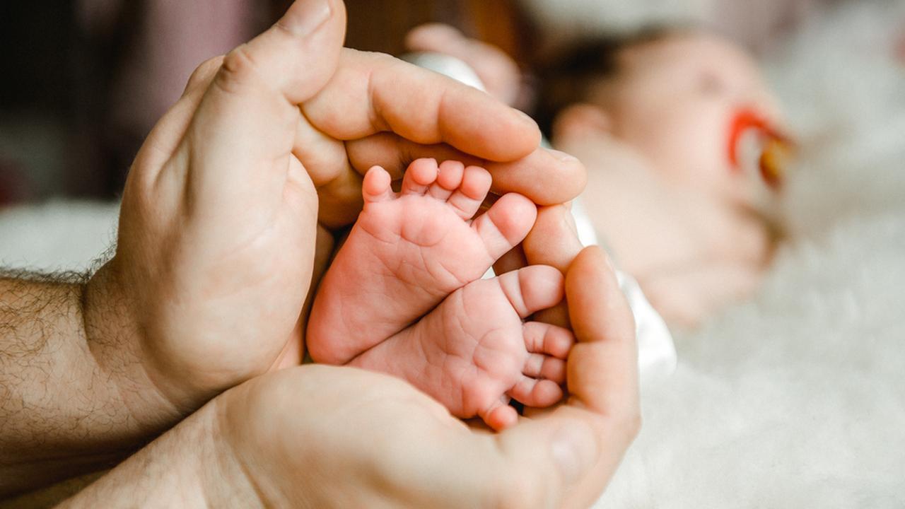 Пяточки младенца в руках родителей
